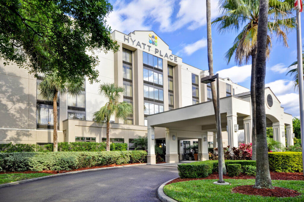 The exterior of Hyatt Place Tampa Airport/Westshore hotel, displaying its modern façade with distinctive signage in the bright Florida sun.