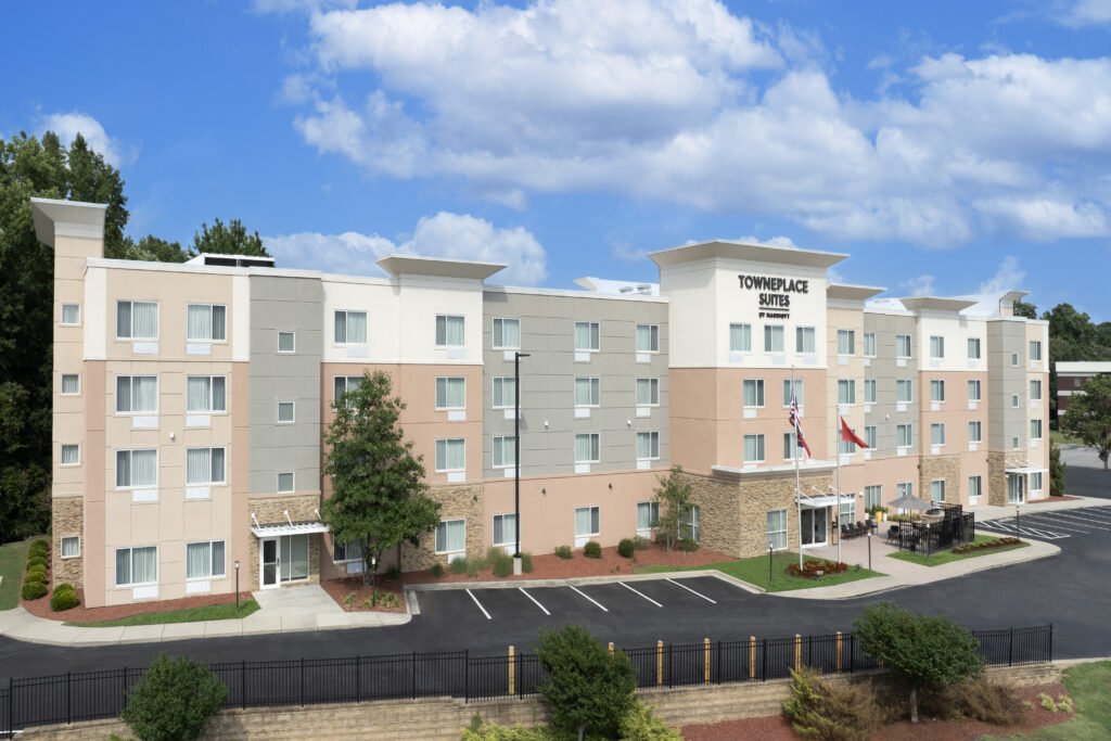 Exterior view of TownePlace Suites Goldsboro, NC, showcasing the hotel's modern architecture and well-lit entrance surrounded by landscaped greenery.